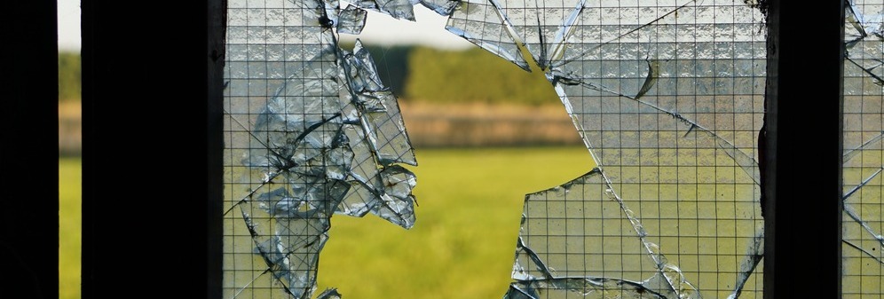 Broken window panes from the inside with a view of green meadows